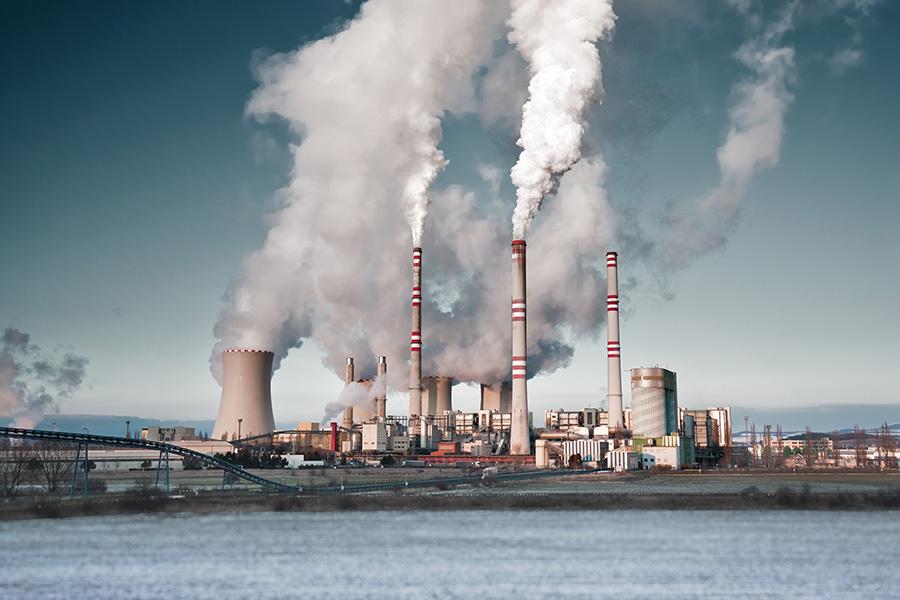 A coal-fired power station in the distance in agricultural landscape. Pocerady, Czech republic | Photo by kamilpetran via Adobe Stock