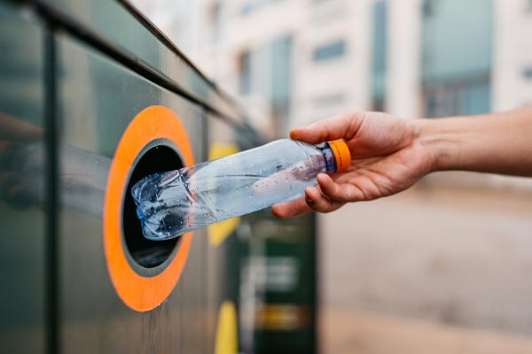 Close-up of a young man putting a water bottle in a recycling bin in Malmo in Sweden